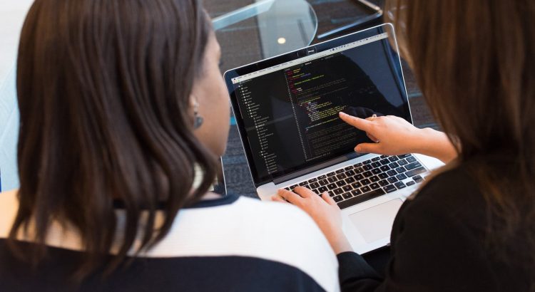 two women looking at the code at laptop