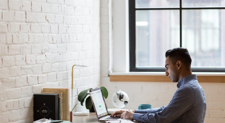 man sitting on green chair while using laptop